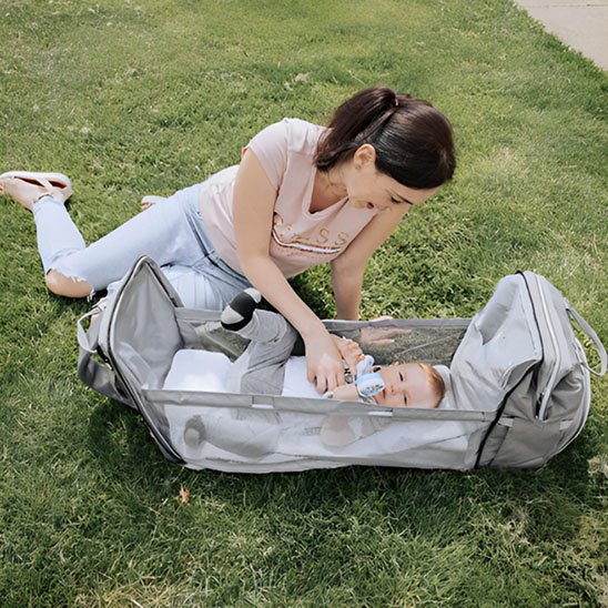 un bébé s'amuse dans son lit bébé pour voyage gris