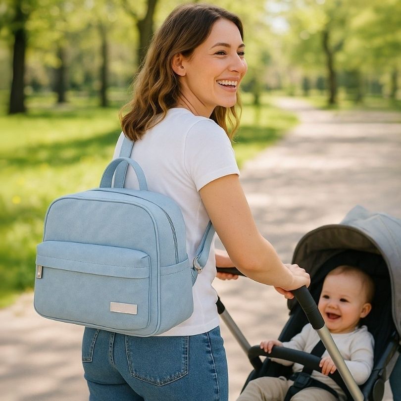 une femme avec un sac à langer bleu en bandoulière promenant son bébé
