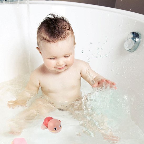 Un bébé qui est en train de jouer avec une tortue dans une baignoire toute calme.
