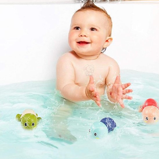 Un bébé qui est en train de jouer avec les trois jouets de bain.