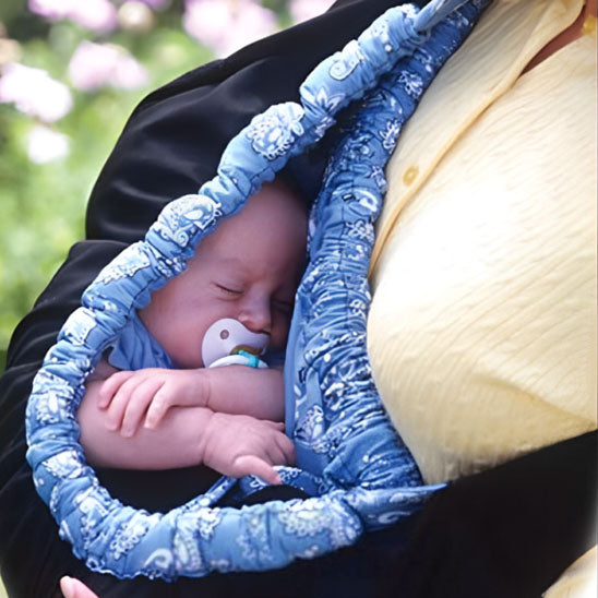 un bébé nouveau-né dort dans une écharpe de portage sling bleu