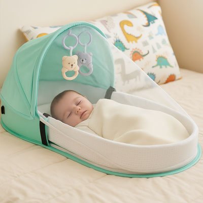 Un bébé dort tranquillement dans un lit bébé pour voyage vert.