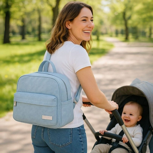 une femme avec un sac à langer bleu en bandoulière promenant son bébé